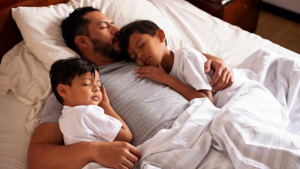 Parent and two children peacefully bedsharing at night — responsive parenting